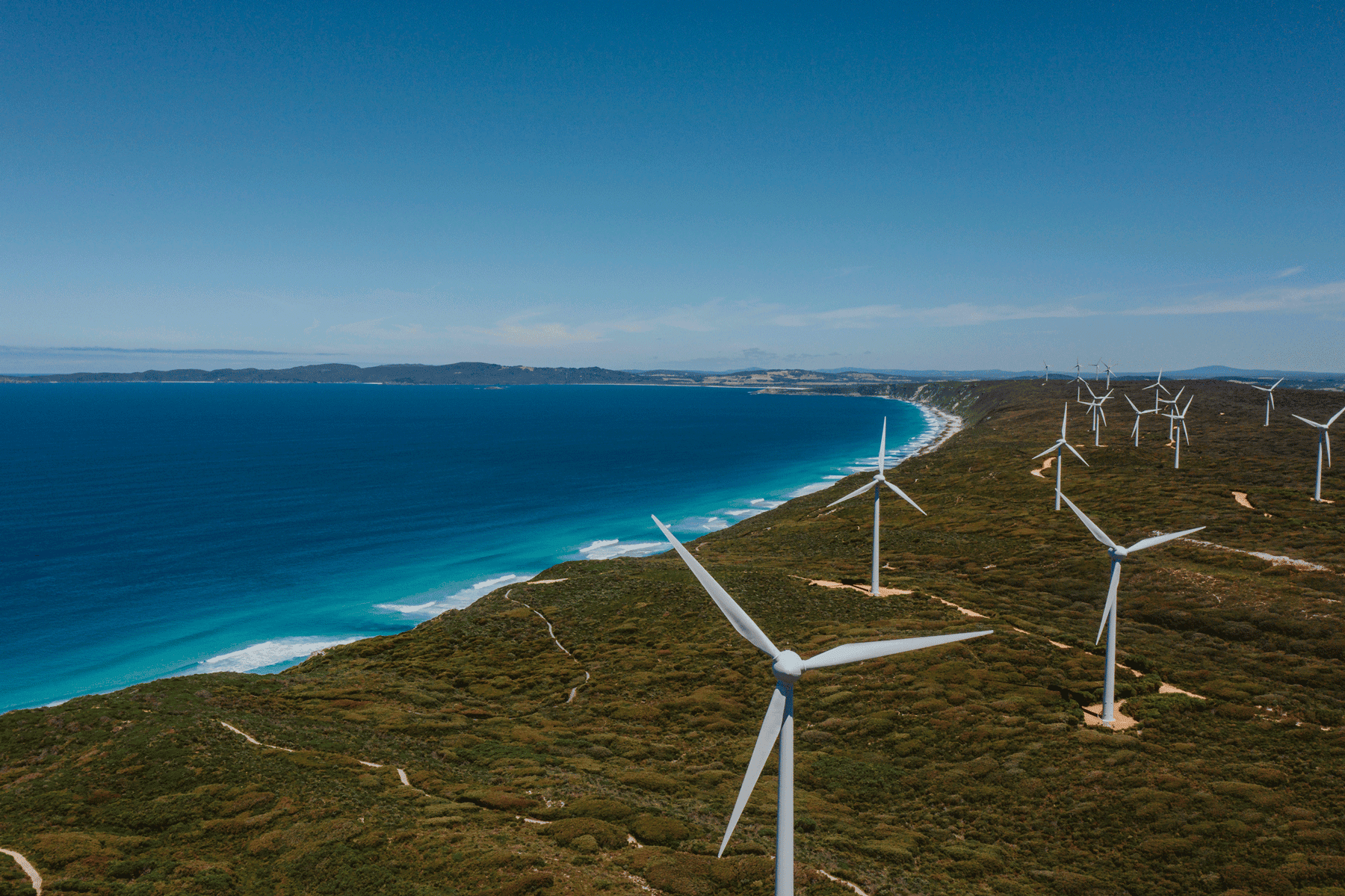 Gentle breeze wind turbines on coastal hillside with ocean views, renewable energy renewable energy source, sustainable wind farm, green energy, ocean coastline, wind power, environmental conservation, renewable energy technology.