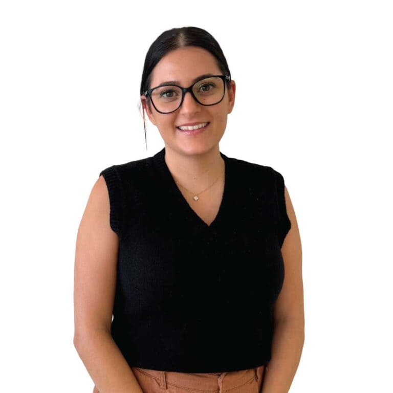 Female young professional wearing black sleeveless sweater and glasses, smiling against plain white background.