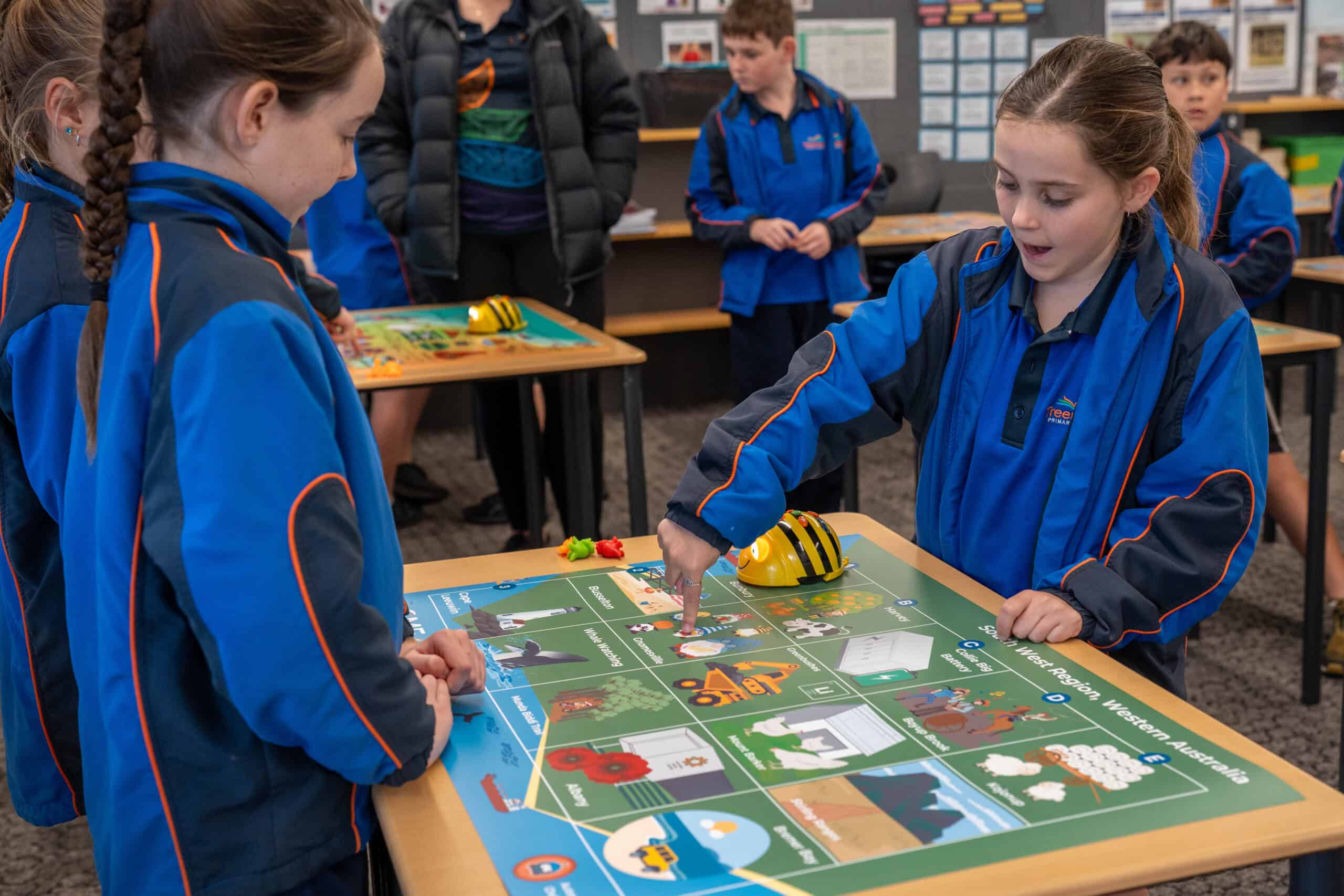 CMEWA students engaging in an interactive educational game at a classroom table, promoting STEM learning and collaborative skills.