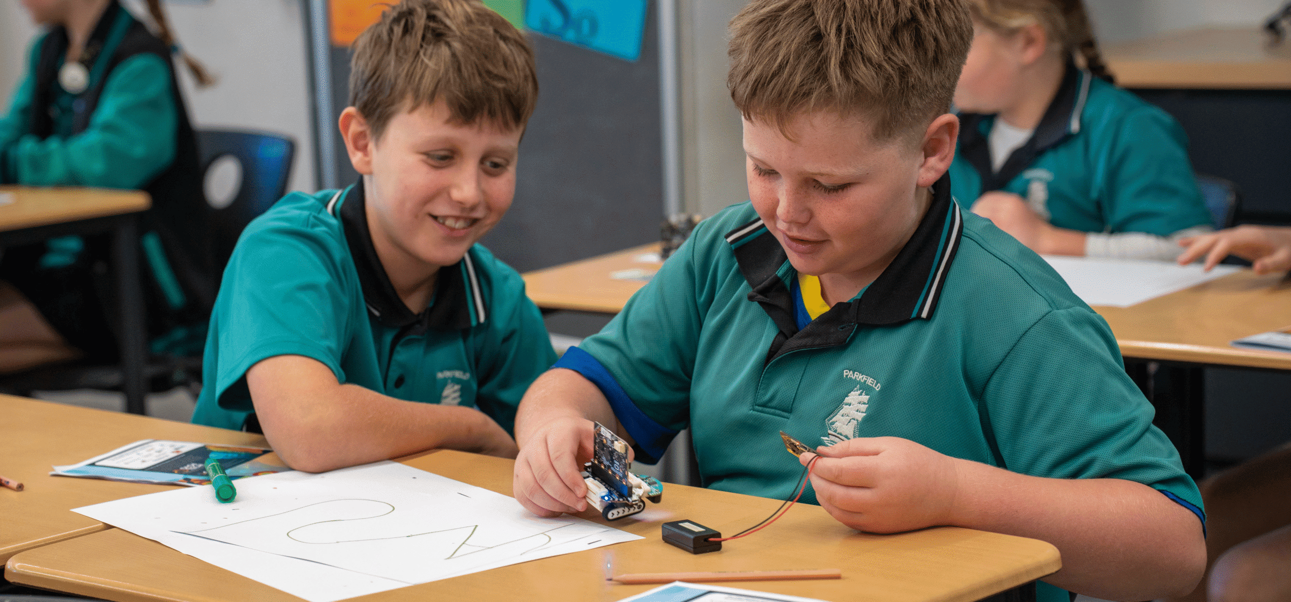 Students engaging in STEM activities with robotics at classroom desk.